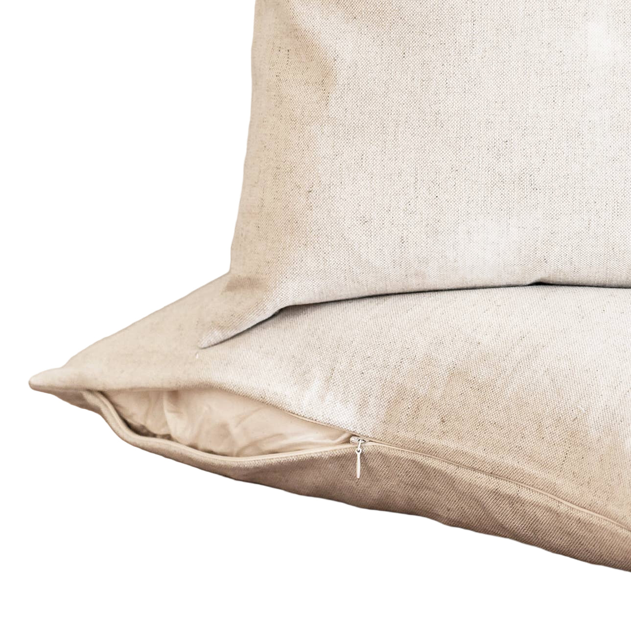 Two beige pillows on a wooden surface with a neutral background