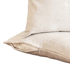 Two beige pillows on a wooden surface with a neutral background